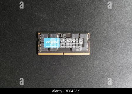 Close-up of a Crucial by Micron DDR5-5600 SO-DIMM memory module, 48GB capacity, labeled as product of Malaysia, displayed against a dark textured surf Stock Photo