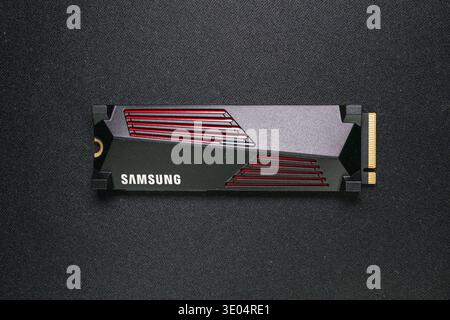Close-up of a Samsung NVMe solid-state drive with red accents on dark fabric surface, showcasing modern computer memory technology Stock Photo