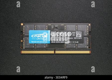 Close-up of a Crucial by Micron 48GB DDR5-5600 SODIMM memory module, labeled as product of Malaysia, displayed against textured black surface. Stock Photo