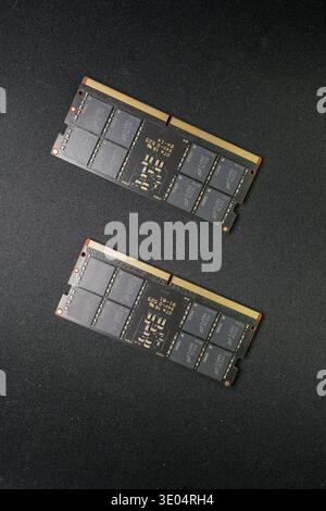 Two DDR5 RAM sticks with gold contacts and black PCBs, showcasing modern computer memory technology against a dark textured surface. Stock Photo
