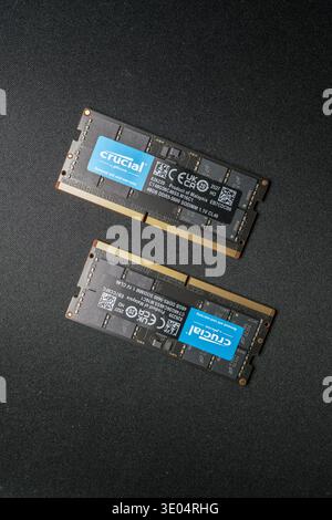 Two Crucial DDR5 SODIMM RAM sticks displayed on dark textured surface, showcasing product labeling, specifications, and gold contacts. Stock Photo