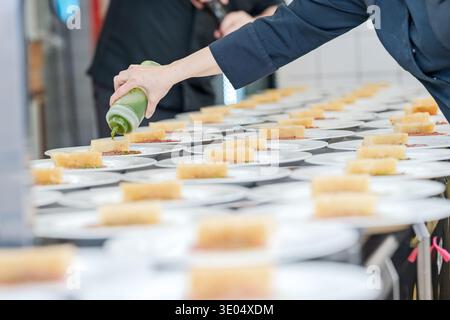 Chef plating gourmet food with sauce in professional kitchen Stock Photo