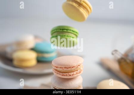 close-up of pastel-colored macarons on a minimalist tabletop, featuring stacked and mid-air lemon, pistachio, peach and turquoise confections, soft na Stock Photo