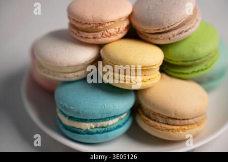 close-up of a colorful stack of pastel macarons on a white plate; soft studio lighting highlights delicate almond shells, creamy fillings and textures Stock Photo