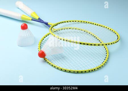 Badminton shuttlecocks and rackets on light blue background Stock Photo