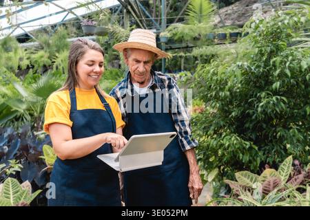 Multigenerational people work at greenhouse doing plants inspection with tablet - Small business farming and e-commerce. Farmers use digital technolog Stock Photo