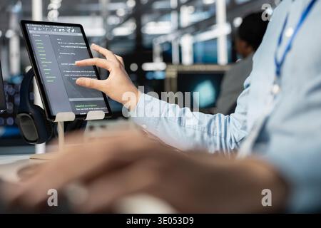 Close up of software developer using tablet in data center, managing server virtualization, running scripts. IT professional using programming language on touchscreen device in server farm Stock Photo