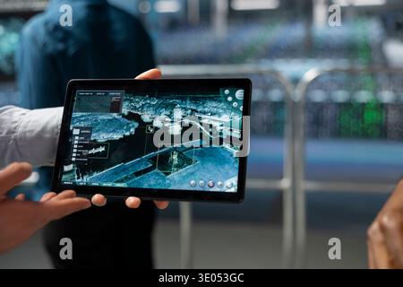 Close up of engineer presenting geospatial data to a soldier in server room, working on military defense tactics and high tech equipment. Military data center personnel ensure national security. Stock Photo