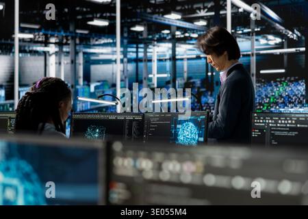 Engineers using devices in data center to install upgraded server racks systems helped by machine learning AI. Server room colleagues upgrading gear using artificial intelligence neural networks Stock Photo