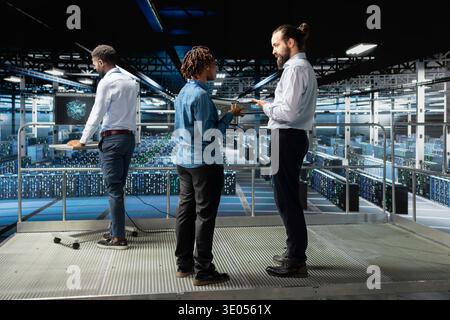 Data center engineers team performing maintenance on supercomputers with artificial intelligence. Server room staff members upgrading rigs used for machine learning, software engineering. Stock Photo