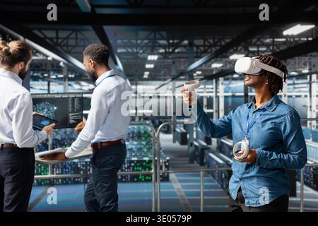 African american engineer with VR glasses using AI neural network systems, ensuring big data visualization within server farm operations. Woman uses programming language and virtual reality. Stock Photo