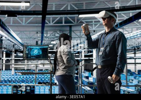 Server room IT expert using VR headset to adjust AI model parameters improving operations. Data center engineer using virtual reality technology adjusting artificial intelligence algorithms Stock Photo