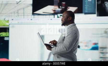 Joyful man using streaming services on laptop, receiving personalized video recommendations. Upbeat user using notebook, enjoying access to wide variety of online clips, camera A Stock Photo