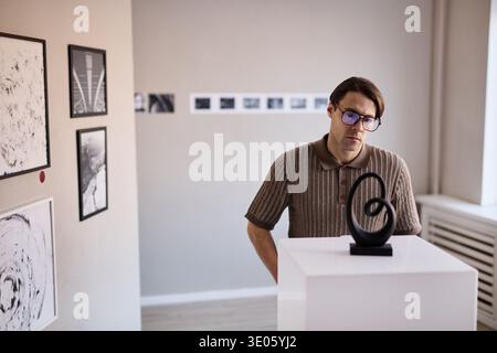 Young Adult Caucasian Man Observing Abstract Sculpture in Art Gallery Stock Photo