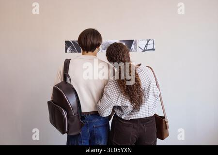 Young Adult Man and Young Adult Woman Observing Artworks in Gallery Setting Stock Photo