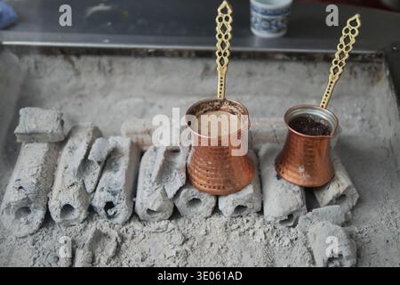 Turkish Coffee brewing on hot coals in a simple setup outdoors Stock Photo