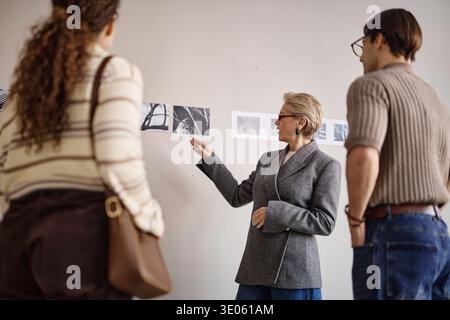 Middle Aged Caucasian Woman Discussing Black and White Photographs with Adults Stock Photo