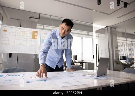 Concentrated millennial male business analyst benchmarking project results using statistics Stock Photo