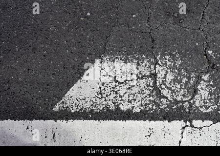 Urban Texture of Cracked Road Surface and Aged White Painted Markings Stock Photo