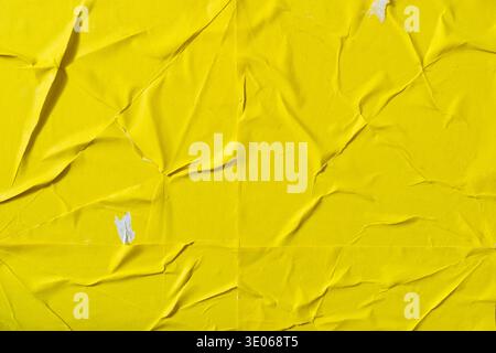 Wrinkled Yellow Poster Texture Glued on Urban Wall Surface Stock Photo