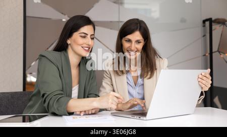 Two businesswomen working on laptop at desk in contemporary office Stock Photo