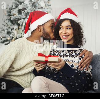 Young man giving her girlfriend present and kissing cheek Stock Photo