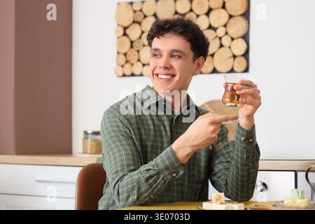 Young man with Turkish tea at table in kitchen Stock Photo