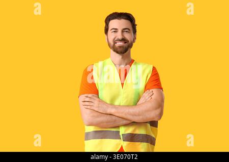 Young happy male construction worker in uniform on yellow background Stock Photo