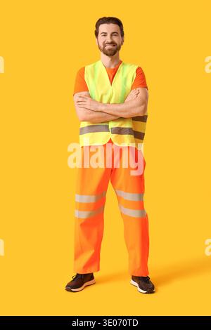 Young happy male construction worker in uniform on yellow background Stock Photo