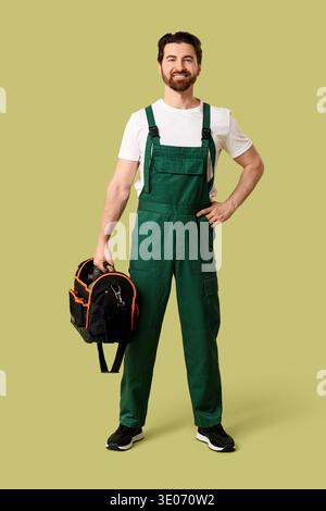 Young happy male painter with tools bag on green background Stock Photo