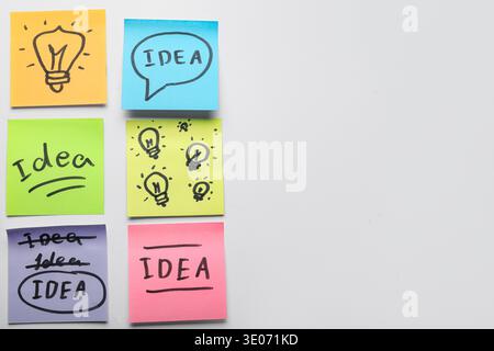 Sticky notes with drawn light bulbs and words IDEA on grey background. Business idea concept Stock Photo