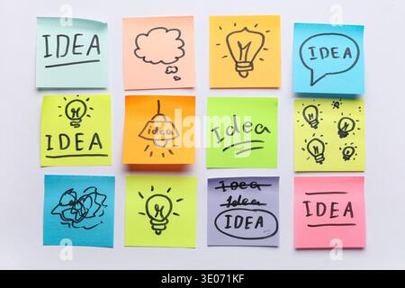 Sticky notes with drawn light bulbs and words IDEA on grey background. Business idea concept Stock Photo