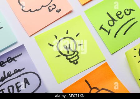 Sticky notes with drawn light bulbs and words IDEA on grey background. Business idea concept Stock Photo