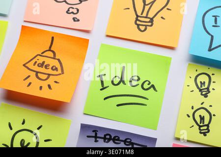 Sticky notes with drawn light bulbs and words IDEA on grey background. Business idea concept Stock Photo