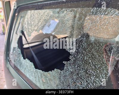 Thief broken car window. Criminal incident and vandalism on the city streets. Stock Photo