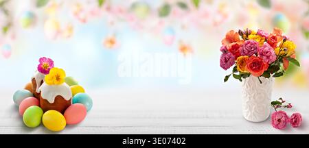 A white background with a cake and a vase of flowers. The cake is decorated with eggs and the flowers are in a vase Stock Photo