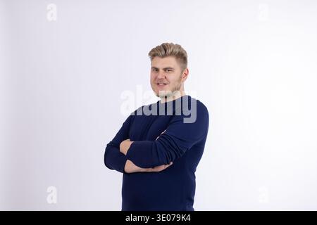 Man in blue sweater posing with arms crossed Stock Photo