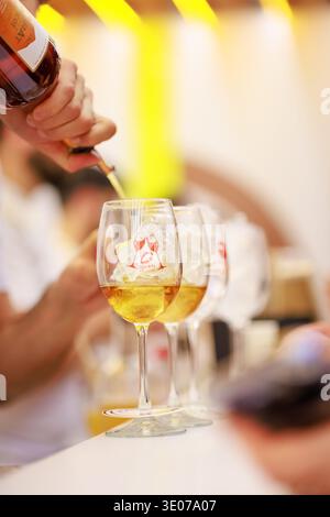 In Yerevan Wine Days festival, white wine is poured over ice into branded glasses, highlighting the refined tasting experience and festive atmosphere. Stock Photo