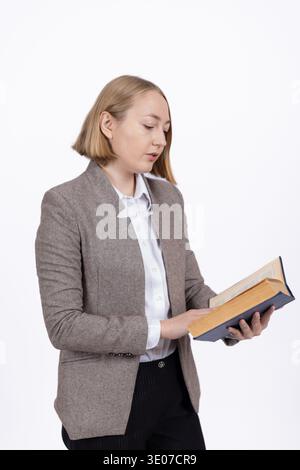 Woman in formal attire holding and reading a book Stock Photo