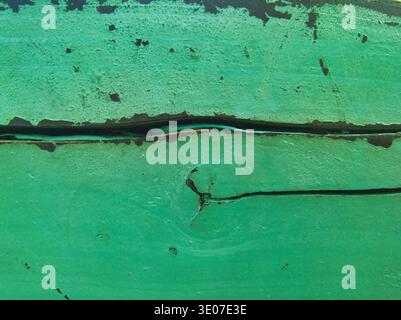 A vivid macro shot of cracked, turquoise-painted wood. The composition features a natural heart-shaped knot and peeling paint layers, creating a roman Stock Photo