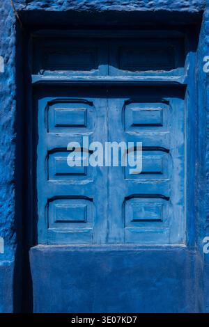 Bright blue wooden door set in traditional house wall in El Cotillo village Fuerteventura Canary Islands Spain colorful architectural detail typical o Stock Photo