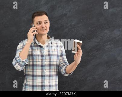 Young man with takeaway coffee talking on phone Stock Photo