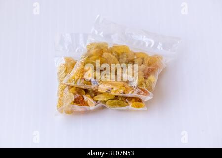 Two transparent plastic packets of golden raisins isolated on a white background. Close-up of dried fruits in clear food packaging, perfect for retail Stock Photo