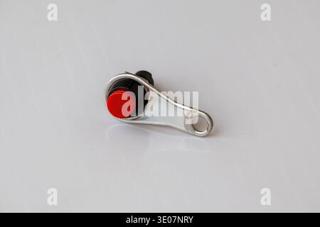 Close-up of a universal motorcycle handlebar push button switch with red button on white background. Control switch for motorbike horn, starter, or fo Stock Photo