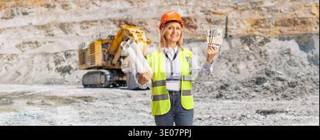 Female engineer holding blueprints and money at a quarry Stock Photo