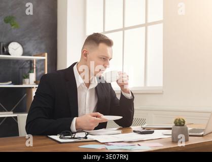 Young male manager working with papers and drinking coffee Stock Photo