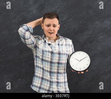 Stressed man holding clock in studio Stock Photo