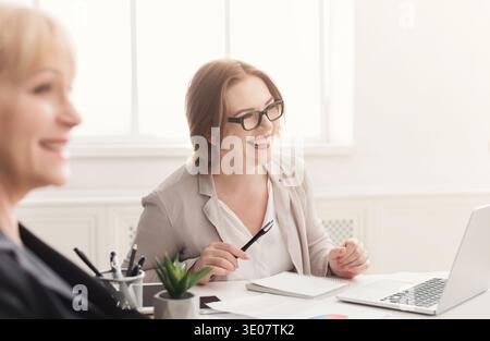 Two happy women working together in modern office Stock Photo