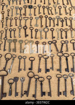 Large collection of antique skeleton keys arranged on a board. Different shapes, sizes and aged metal textures create a historic pattern. Stock Photo