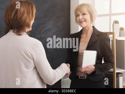 Two business women shaking hands in office Stock Photo